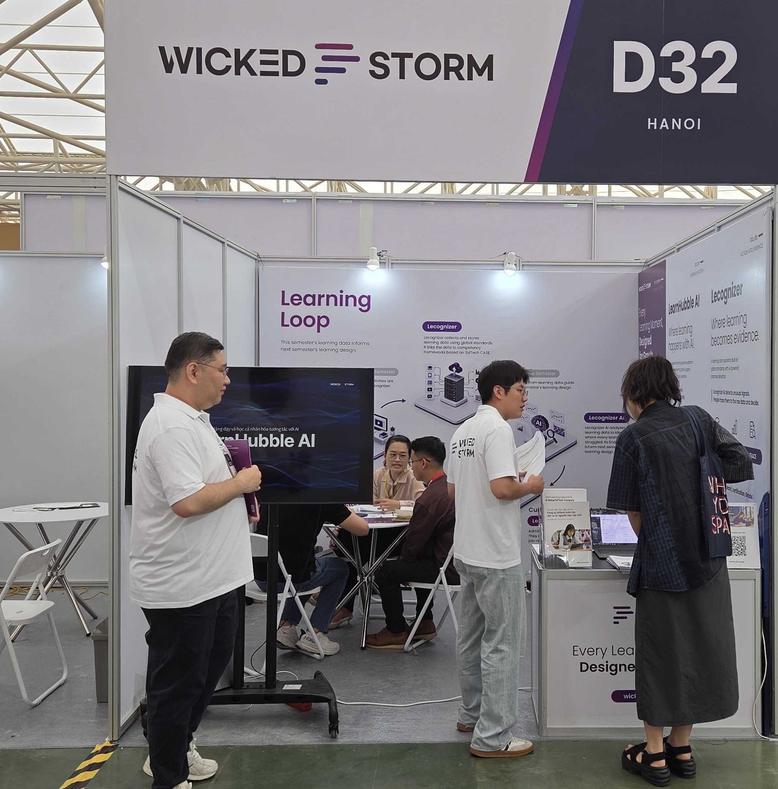 WICKED STORM D32 간판 아래 부스 앞에서 위키드스톰 직원들이 관람객에게 제품을 설명하고, 안쪽 테이블에서 상담이 진행되는 모습